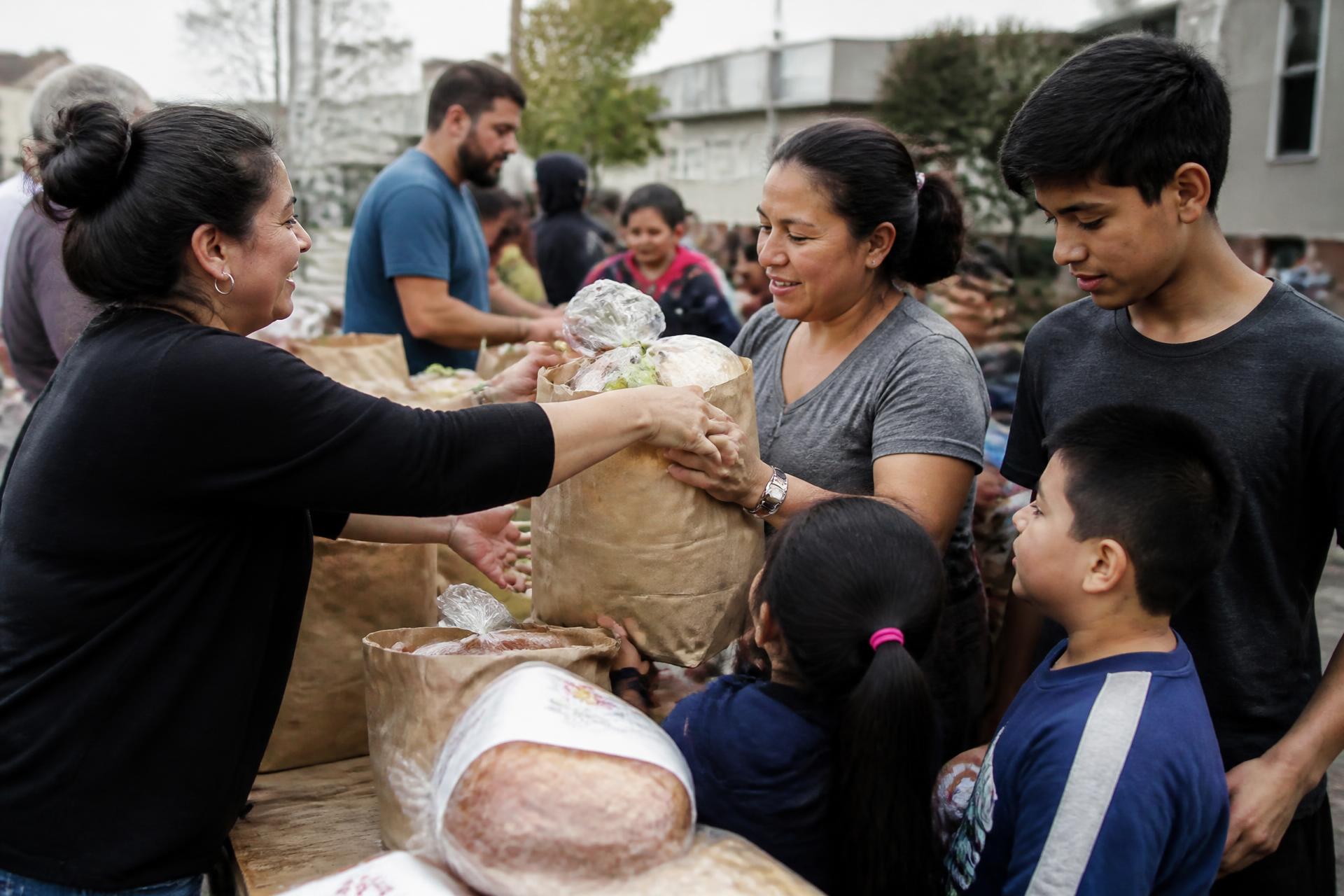 Volunteers handing bags of groceries to a family at a community food distribution
