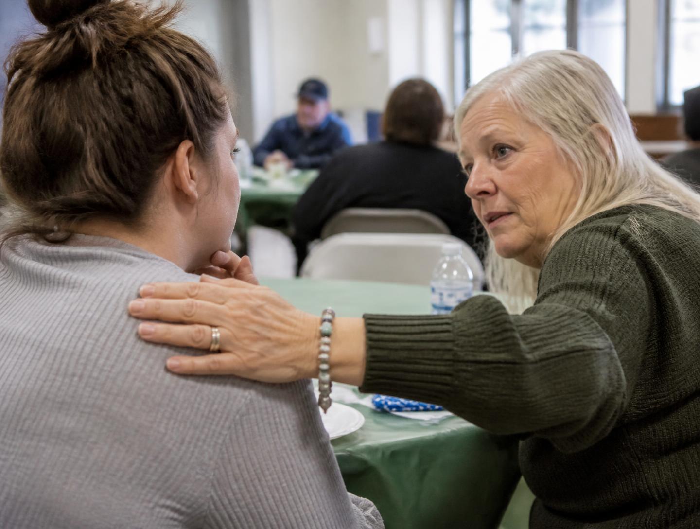 A volunteer resting a hand on someone's shoulder during a quiet conversation